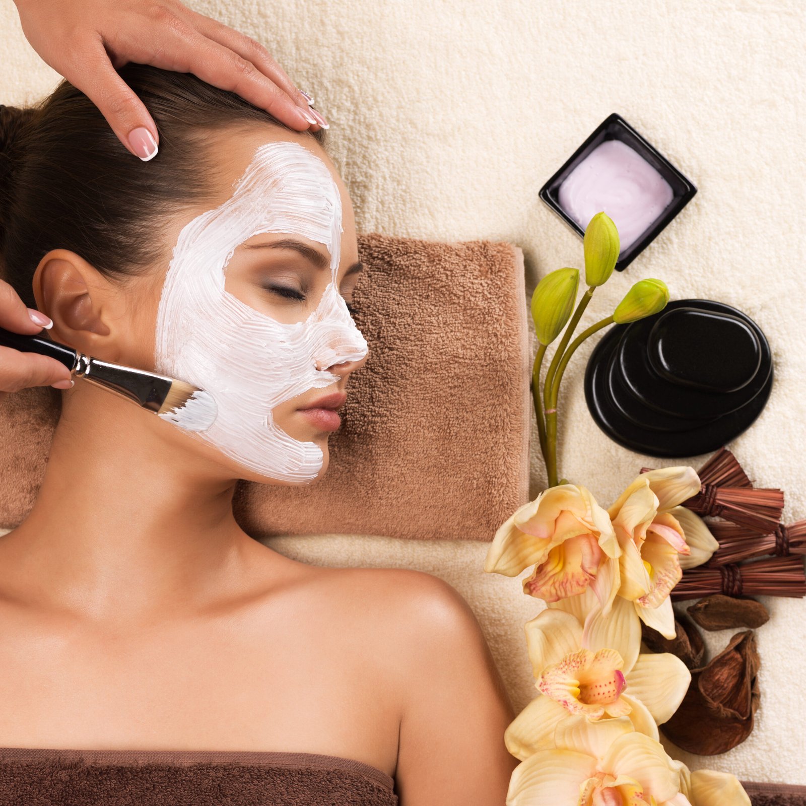 Beautiful young woman having a facial cosmetic mask at spa salon.